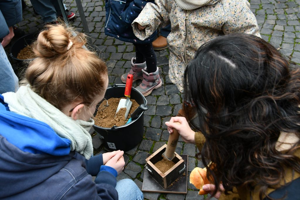 Kinder fertigen handgeformte Stampflehm‑Teelichthalter auf dem Nikolausmarkt in Meerbusch, Lank‑Latum